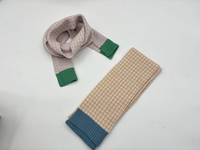 Twee gebreide sjaals op wit oppervlak: lila met groene manchetten en beige met blauwe geribbelde manchet.