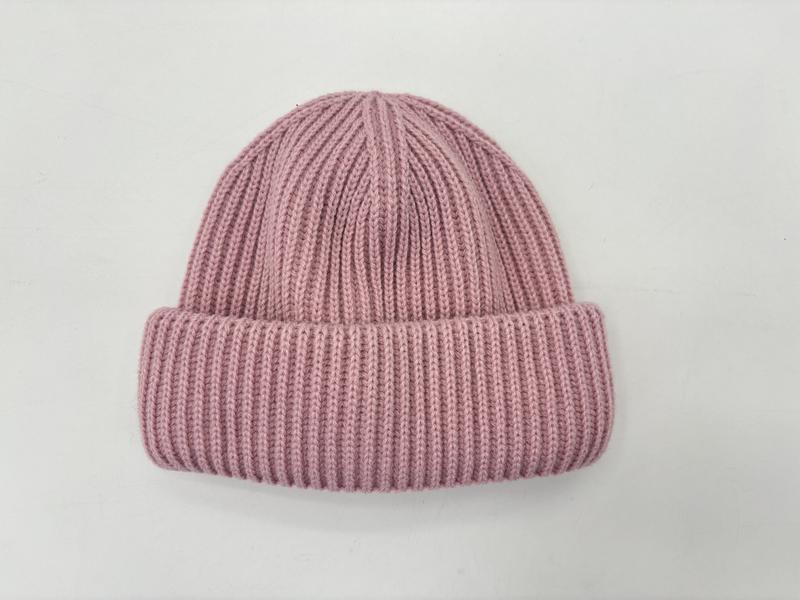 Platte weergave van een stoffig roze geribbelde gebreide wintermuts met omgeslagen rand op witte achtergrond.
