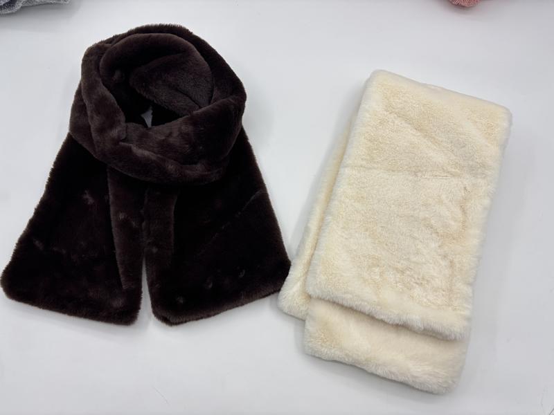 Twee faux fur sjaals naast elkaar: één donkerbruine gedrapeerd en één crèmewitte gevouwen