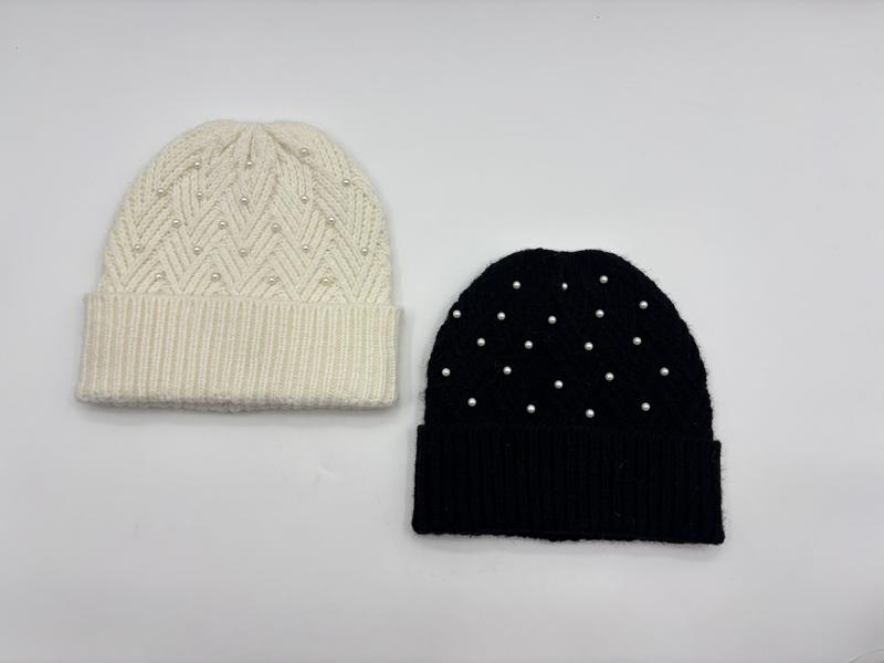 Twee gebreide beanies met parelversiering naast elkaar: crème chevronpatroon en effen zwart
