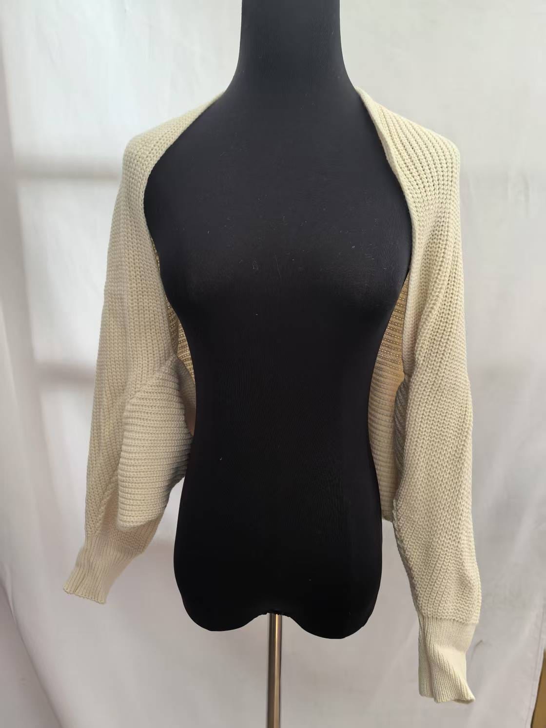 Crème grofgebreid open bolero vest met lange mouwen en geribbelde manchetten op zwart paspop.
