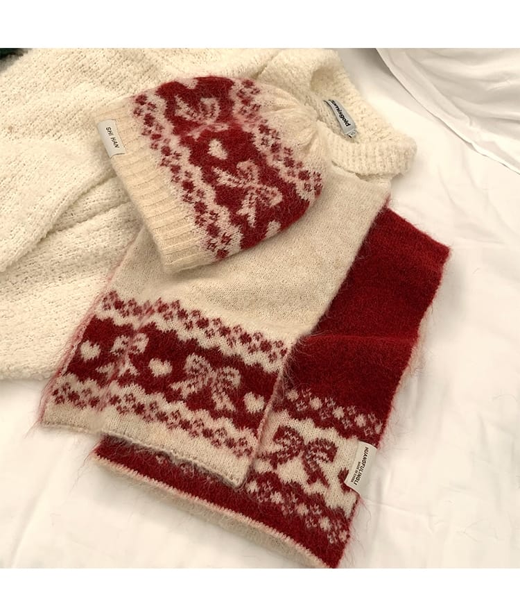 Crème en rode Fair Isle gebreide muts en bijpassende sjaal met hart- en bloemmotieven op witte achtergrond.