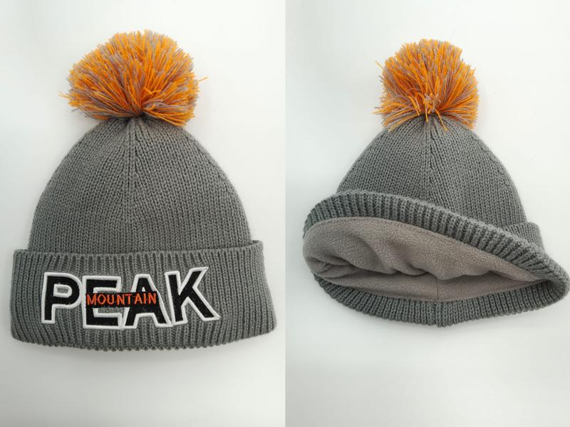 Grijze gebreide wintermuts met oranje pompon