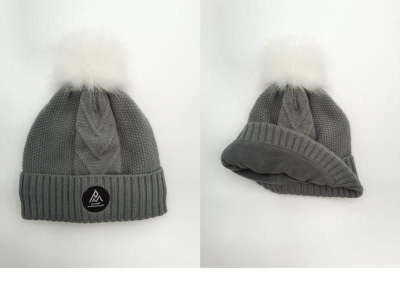 Grijze kabelgebreide wintermuts met witte kunstbont pompon