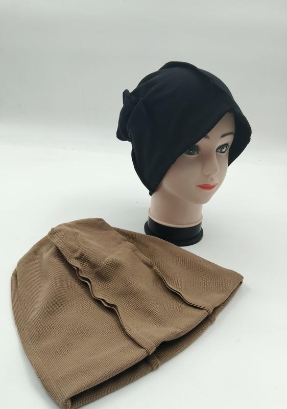 Zwarte slouchy beanie hijab underscarf op paspop met beige getextureerde binnenmuts ernaast.