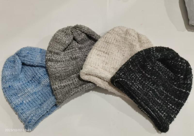 Vier handgebreide wollen mutsen in blauw