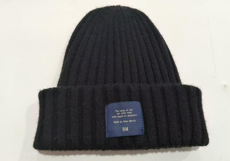 Zwarte chunky geribbelde gebreide wintermuts met omgeslagen rand en blauw merklabel