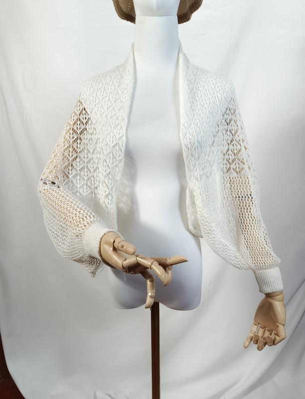 Wit kanten gebreid cropped bolero vestje met lange ballonmouwen.