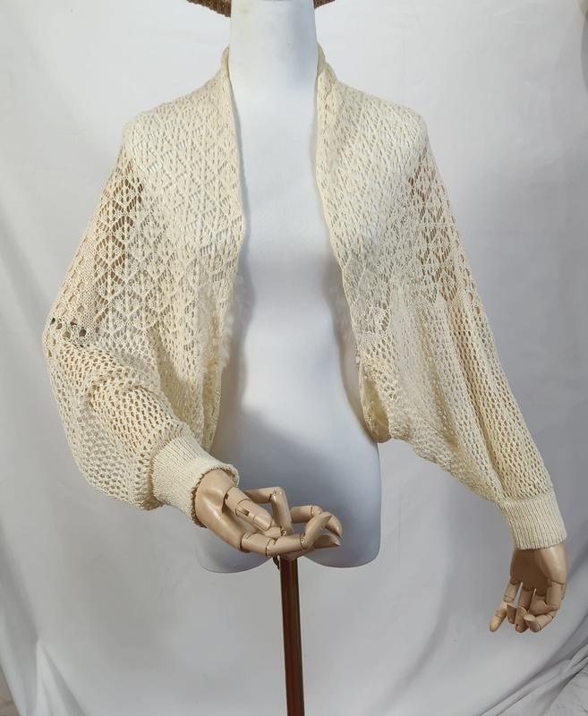 `Crème opengebreide bolero met gehaakt patroon en wijde bisschopsmouwen`