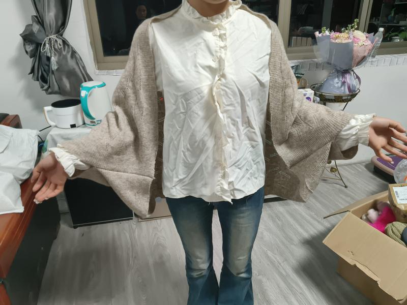 `Oversized beige gebreide cardigan gecombineerd met een crèmekleurig gewatteerd overhemd met knopen.`