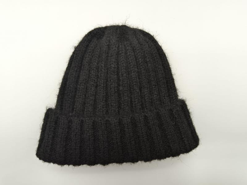 Zwarte grove gebreide beanie muts met omgeslagen rand en grove ribstructuur.