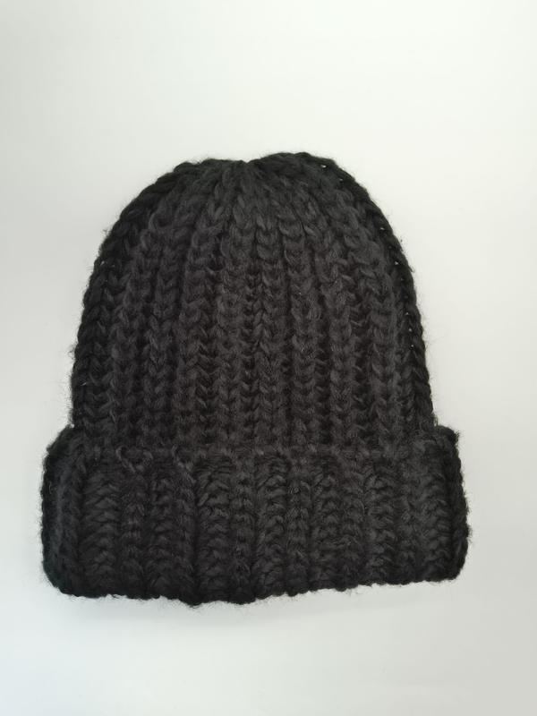 Zwarte oversized gebreide muts met grove ribstructuur en omgeslagen rand voor de winter.