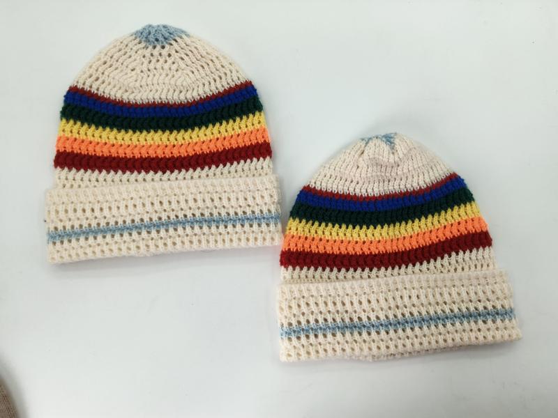 Twee handgemaakte gehaakte crème beanies met regenboogstrepen in blauw