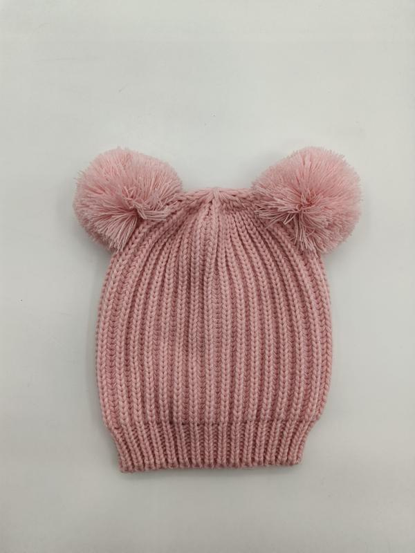 Roze geribbelde gebreide babymuts met twee pluizige pompons bovenop