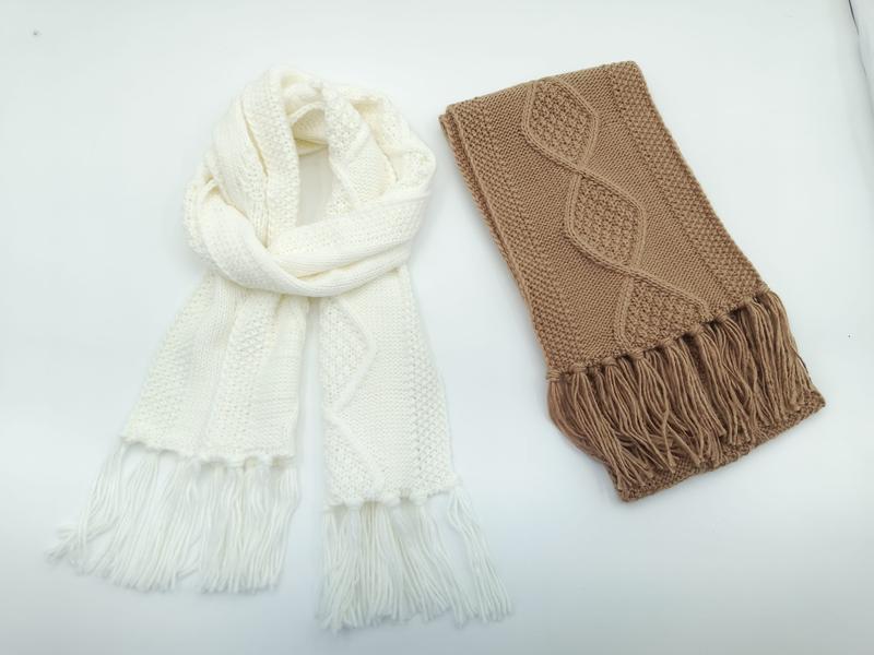 Twee kabelgebreide wintershawls met franje op witte achtergrond: crème infinity-shawl en gevouwen camelkleurige shawl.