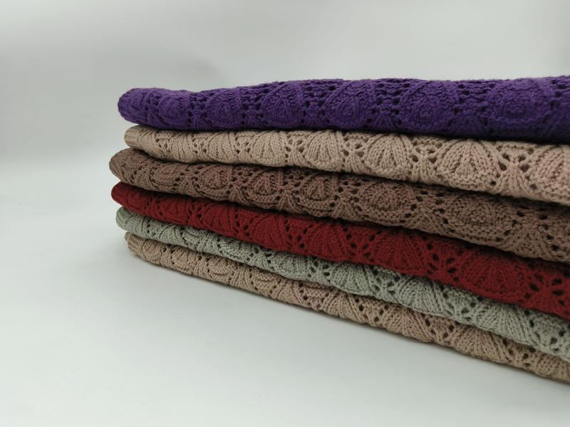 Stapel van zes gevouwen kanten gebreide plaids in paars