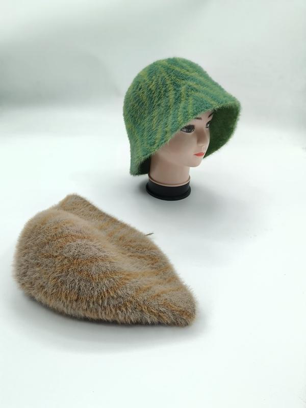 Groene gestreepte fuzzy gebreide bucket hat op mannequinhoofd met bijpassende beige flat cap op witte ondergrond.