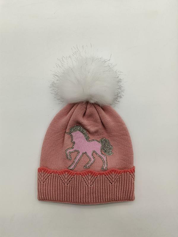 Roze gebreide meisjesmuts met eenhoorn-strass applicatie en witte pluizige pompon.