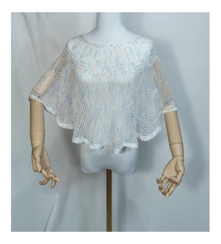 Witte en lichtblauwe open gehaakte mesh poncho cape top op een mannequin met houten armen.