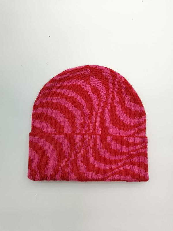 Platte lay van een roze en rode zebra gestreepte gebreide muts met omgeslagen rand op witte achtergrond.