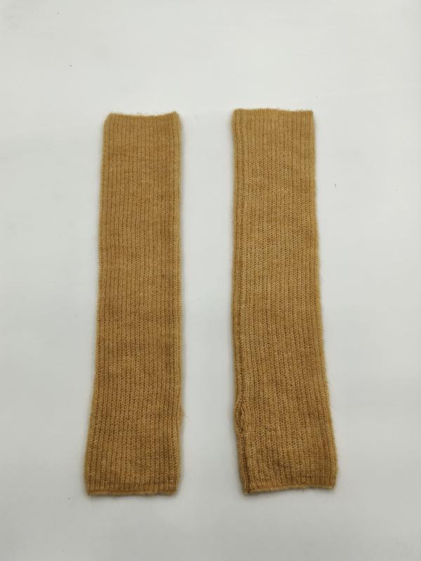 Mosterdgele geribbelde gebreide vingerloze armwarmers plat neergelegd op witte achtergrond.