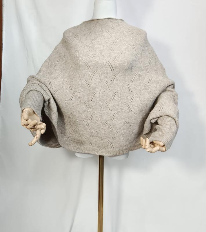 Oversized haverkleurige pointelle gebreide trui met ballonmouwen op een mannequin met houten handen.