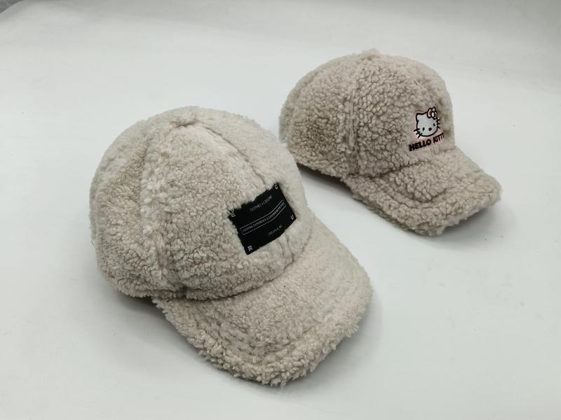 Twee crème sherpa fleece baseball caps: één met zwart labelpatch