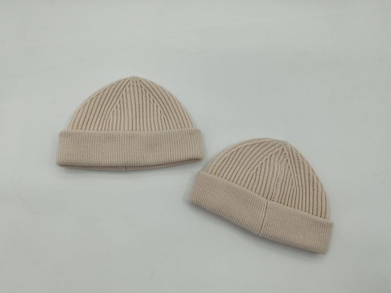 Twee beige geribbelde gebreide beanie mutsen met omslag op witte achtergrond