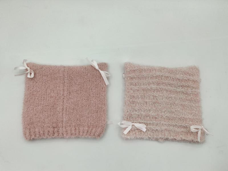 Twee roze gebreide laarsomboorden met witte satijnen strikken