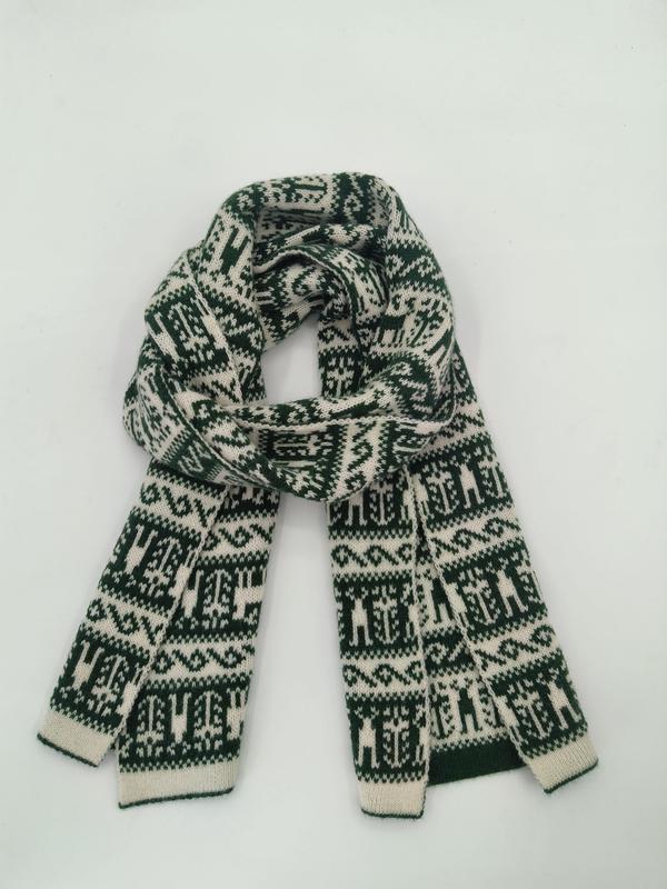 Gevouwen groene en crèmekleurige gebreide sjaal met Fair Isle Nordisch geometrisch patroon op witte achtergrond.