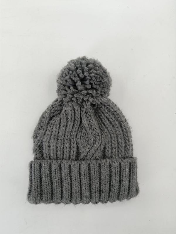 Grijze grove kabelgebreide wintermuts met grote pompon en geribbelde rand