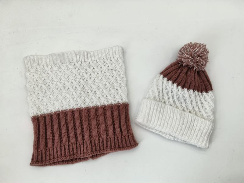 Gebreid winterset met crème en mauve colsjaal met diamantpatroon en bijpassende pompon muts op witte achtergrond.