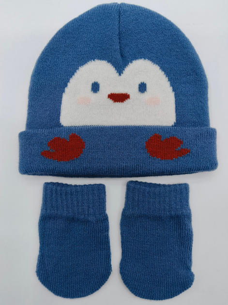 Blauwe gebreide babymuts met pinguïngezicht en bijpassende wantjes op witte achtergrond.
