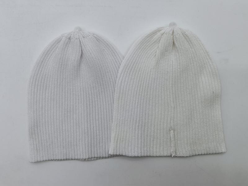 Twee ribgebreide beanie mutsen plat neergelegd: één lichtgrijs en één gebroken wit