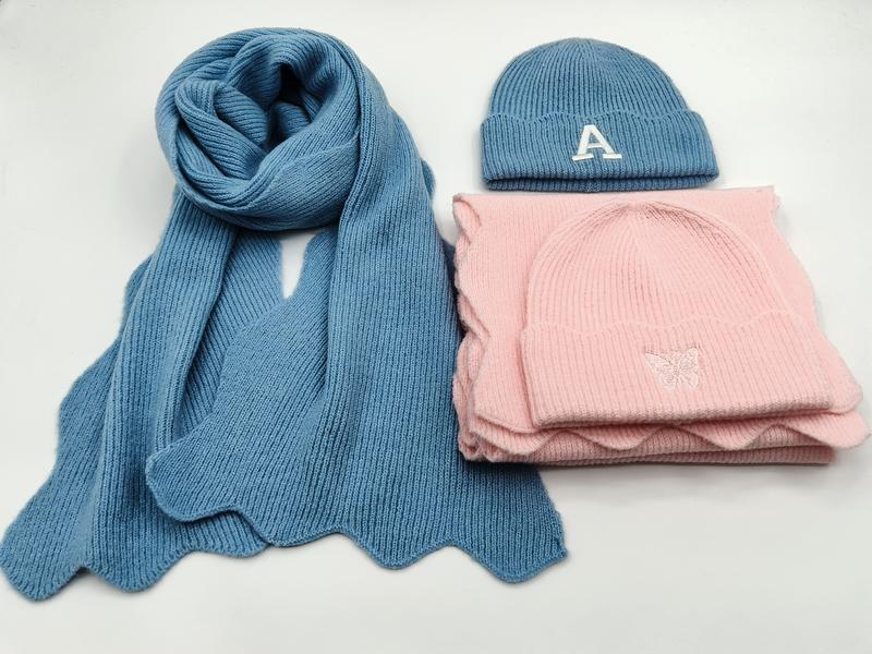 Blauwe ribgebreide sjaal met letter A-muts en roze vlinder-muts met bijpassende roze sjaal