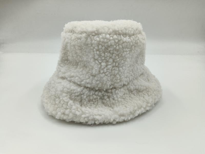 Witte sherpa bucket hat met brede rand en teddy fleece textuur op witte achtergrond.