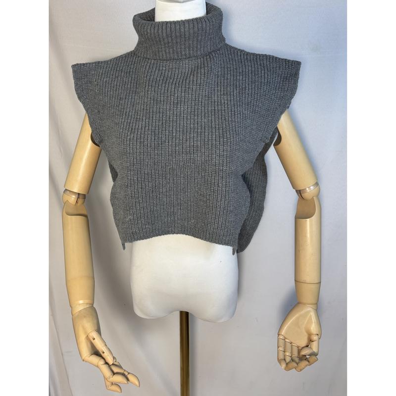 Grijze geribbelde gebreide cropped turtleneck mouwloze trui-vest op een mannequin met houten gelede armen.