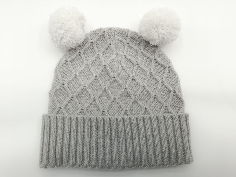 Grijze gebreide babymuts met twee witte pompons en geribbelde rand