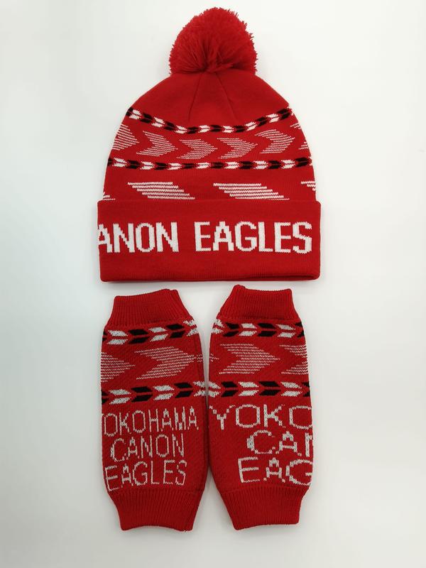 Rode gebreide muts met pompon en bijpassende armwarmers met wit geometrisch pijlpatroon en teamtekst.