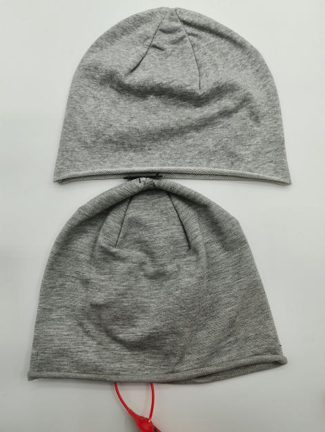 Twee grijze gemêleerde jersey gebreide slouchy beanie mutsen plat neergelegd op witte achtergrond
