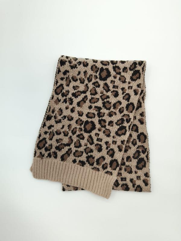Gevouwen beige en zwarte gebreide luipaardprint sjaal met geribbelde rand op witte achtergrond.