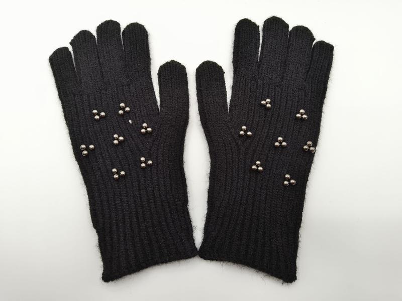 Zwarte geribbelde gebreide winterhandschoenen met zilveren metalen studs op de handrug.