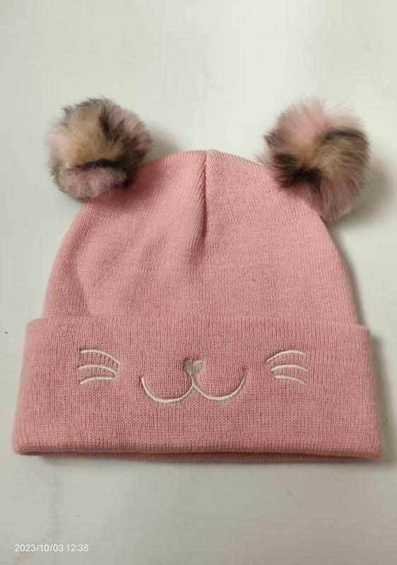 Roze gebreide wintermuts met nepbont pompons en geborduurd kattengezicht - groothandel