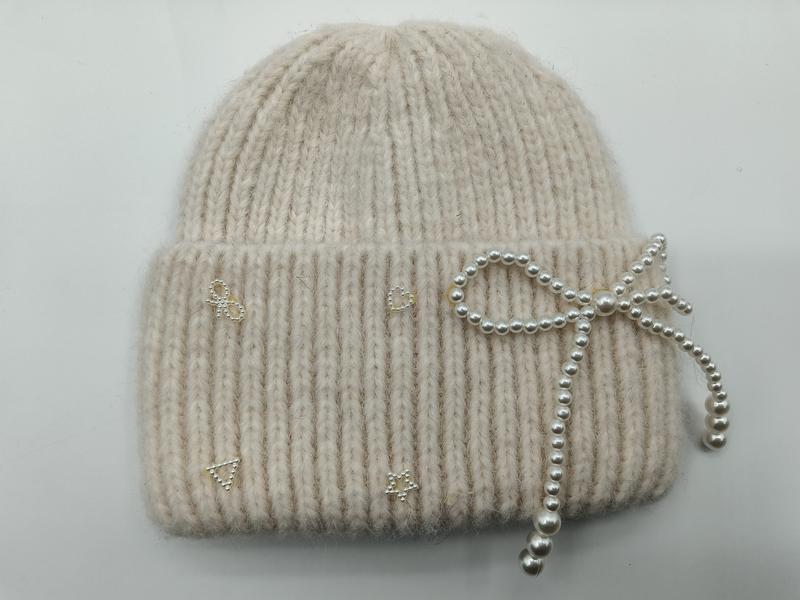 Crème geribd gebreide wintermuts met decoratieve parelstrik en strass-steentjes op de manchet.