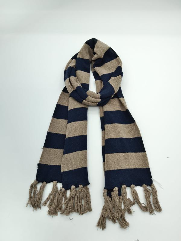 Gestreepte gebreide wintersjaal in marineblauw en beige met kwastjesfranje op witte achtergrond.