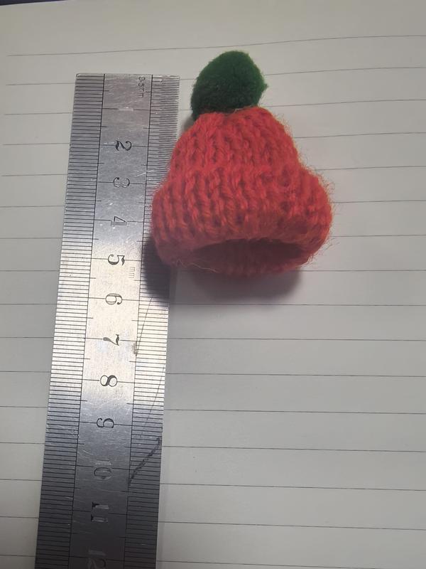 Miniatuur rood gebreid wollen beaniemutje met groene pompon