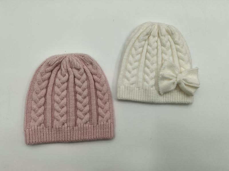 Twee cable knit wintermutsen naast elkaar: één stoffig roze en één gebroken wit