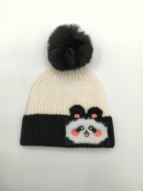 Crème en zwarte geribbelde gebreide wintermuts met panda-gezichtspatch en donkere nepbont pompom.