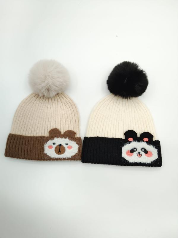 Twee gebreide mutsen met pompon: bruine beer op beige muts en panda op zwart-witte muts.