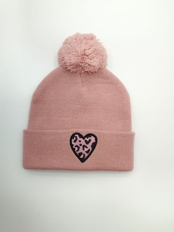 Roze gebreide wintermuts met pluizige pompon en luipaardprint hartenpatch op de omslag.